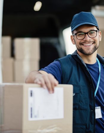 Portrait of happy worker unloading boxes from a delivery van and looking at camera.